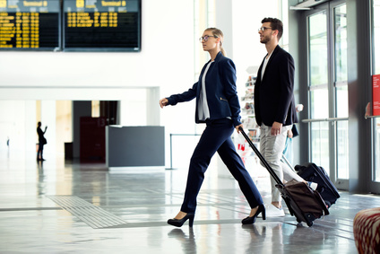 Business professionals walking through an airport, representing skilled workers dependent on an active sponsor licence